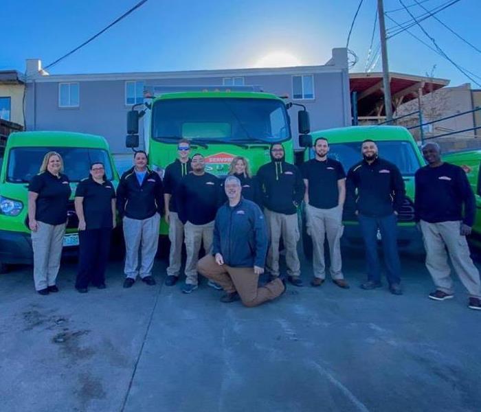 SERVPRO employees stand in front of SERVPRO trucks